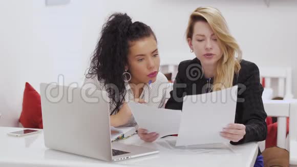 两个女商人在咖啡馆里讨论工作问题并翻阅文件视频的预览图