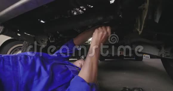 职业男性机械师躺在汽车下面修理它视频的预览图