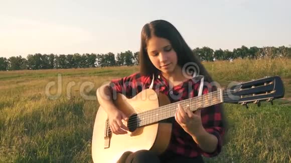 日落时分少女在草地上弹吉他视频的预览图