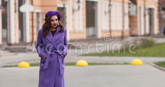 优雅的女人穿着紫色贝雷帽和外套走在街上视频的预览图