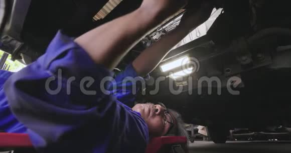 职业男性机械师躺在汽车下面修理它视频的预览图