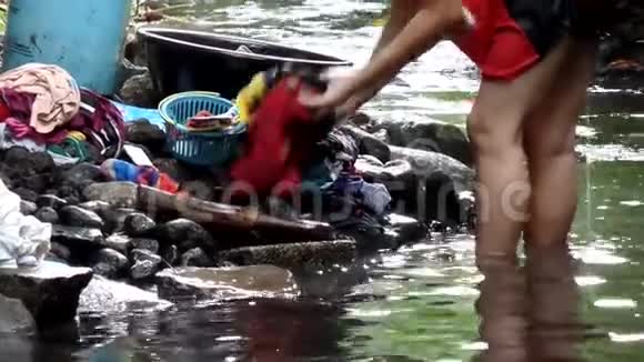 腿浸在膝盖深水里这个女人甚至在污染的河流里洗衣服视频的预览图