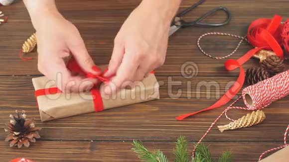 女用手在礼品盒上用红色丝带系蝴蝶结用手工纸包裹视频的预览图