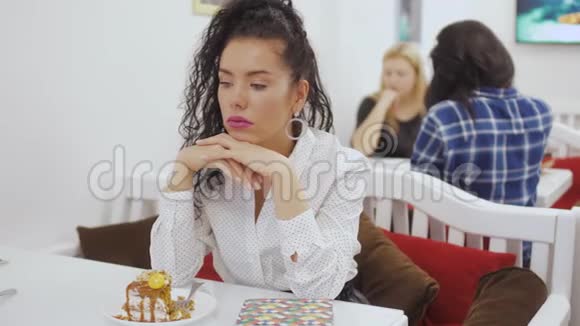 年轻无聊的白种人女人坐在咖啡馆的桌子上视频的预览图