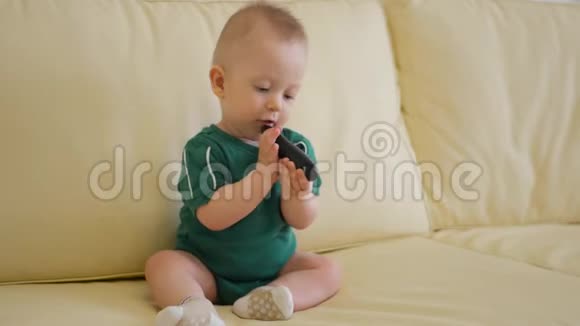 小男孩在家玩遥控器小白种人坐在沙发上看电视视频的预览图