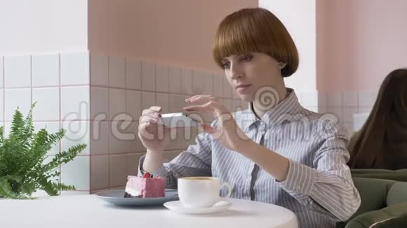 年轻漂亮的红发女孩坐在咖啡馆里做蛋糕的照片今天的问题社交网络60英尺视频的预览图