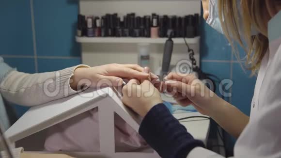 美甲大师在美容院用美甲钳治疗年轻顾客的角质层视频的预览图