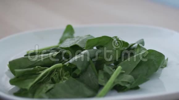菠菜的大绿叶慢慢地落在盘子里视频的预览图