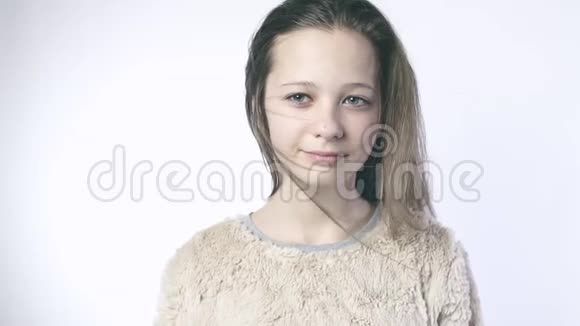 对一个十几岁的女孩慢动作风吹拂着站在白色背景上的美丽女孩的头发特写镜头视频的预览图
