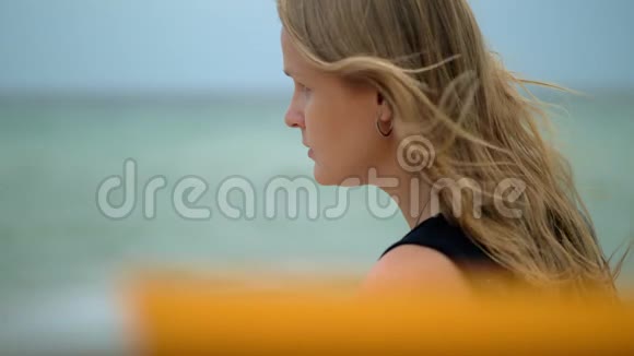 头发在风中飘扬的女人反对大海的肖像视频的预览图
