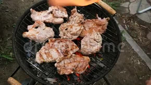 大型美味的生肉牛排在烧烤炉上烤过煤在一个小的户外烧烤视频的预览图