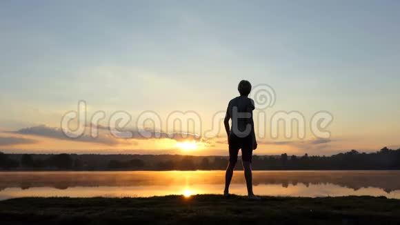 在斯洛莫的日落时分一个独立的人举起拳头在湖上视频的预览图
