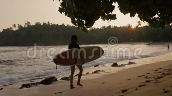 带着冲浪板在海边散步的女孩视频的预览图