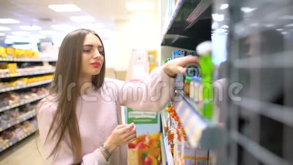 年轻的女人在超市里选择婴儿食品母亲在市场上为孩子选择食物女孩站在附近视频的预览图
