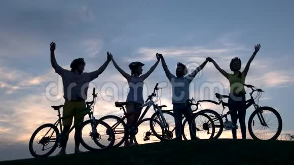 日落时年轻的骑自行车的人手牵手视频的预览图