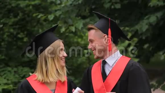 可爱的学生夫妇站在公园里聊天毕业快乐的未来视频的预览图