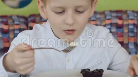 英俊的微笑男孩在咖啡馆里享用美味的甜点视频的预览图