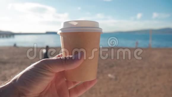 游客拿着一杯热咖啡靠在海滩和蓝海上旅游与旅游理念视频的预览图