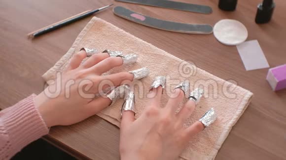 去除指甲中的凝胶抛光双手上都是带箔的手指特写的手上景视频的预览图