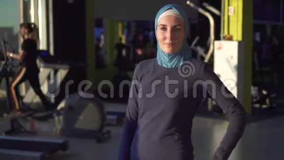 一个年轻的穆斯林运动女孩戴着头巾在一个时髦的健身房里的画像视频的预览图