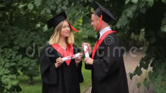 快乐的男女毕业生在公园里聊天毕业日视频的预览图