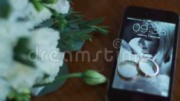 手机上的结婚戒指的特写镜头壁纸上的情侣照片就在旁边视频的预览图
