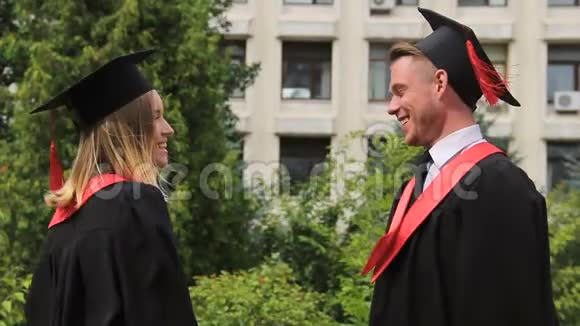 毕业礼服上的金发女郎在领取毕业证书后拥抱最好的朋友视频的预览图