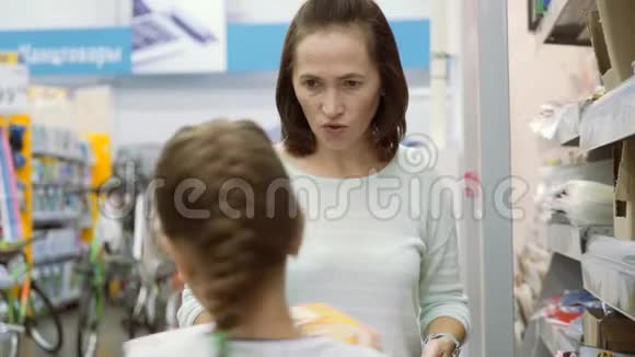 妈妈选择在商店买文具为上学的第一天做准备女人在商店里选择笔记本视频的预览图