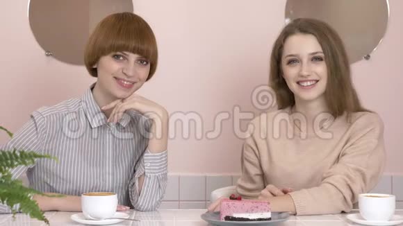 两个年轻的白种人女孩坐在咖啡馆里微笑着看着相机肖像咖啡馆里的女孩60视频的预览图