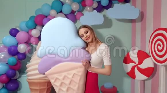 一个可爱的女孩拿着一个巨大的冰淇淋在工作室的背景上巨大的糖果视频的预览图