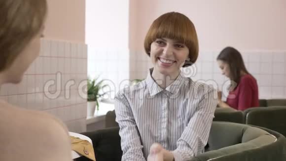三个白种人年轻女孩坐在咖啡馆里微笑交谈对话有趣的故事八卦的概念视频的预览图
