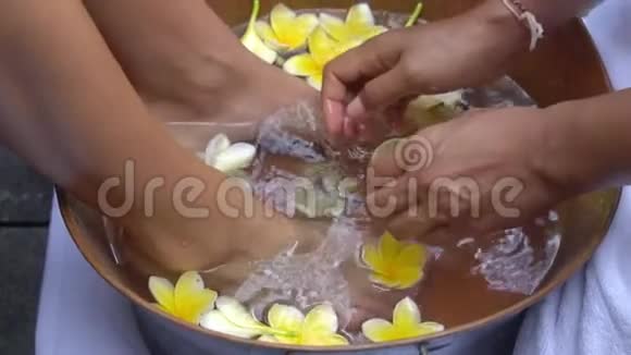 美容师为客户女孩做足浴用清水和鲜花养生视频的预览图