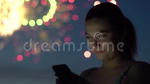 一个女孩在烟火中使用智能手机慢动作视频的预览图