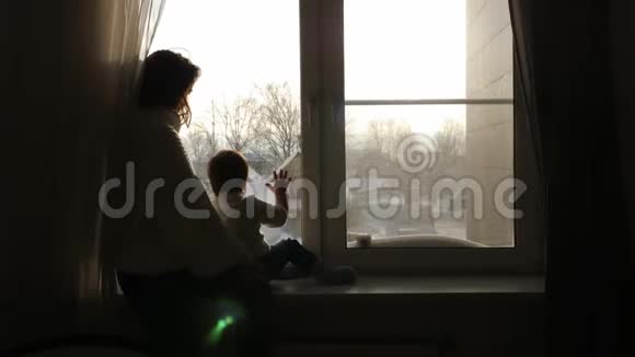 冬天妈妈和儿子坐在房子的大窗户上视频的预览图