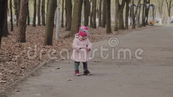 漂亮的小女孩独自在公园里散步视频的预览图