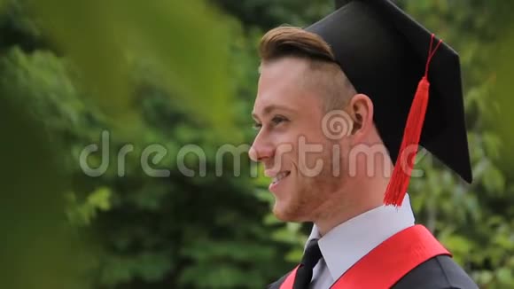 喜笑颜开的男毕业生拿着文凭摆姿势拍照视频的预览图