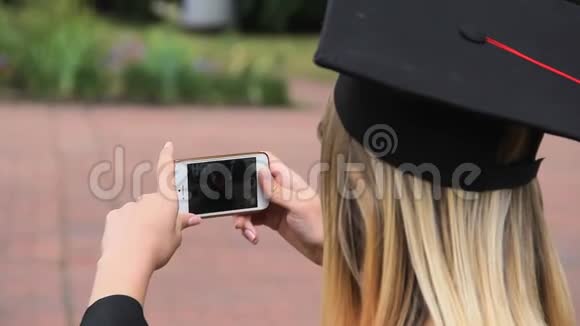 女毕业生用手机拍朋友的照片并竖起大拇指视频的预览图
