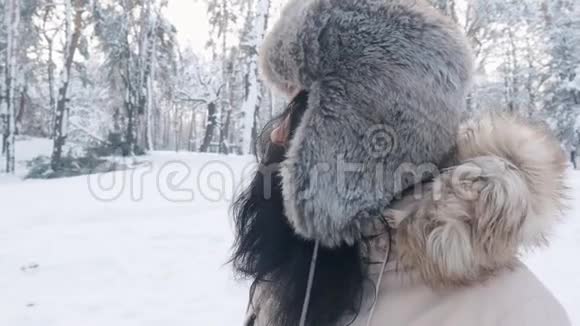 在冬天的雪林里特写一幅戴帽子的美丽年轻女子的肖像视频的预览图