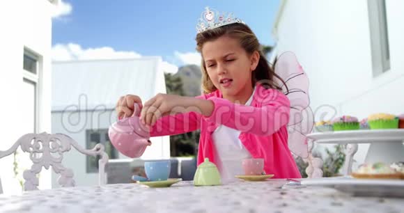 穿着仙女服装的女孩把茶倒进4k杯视频的预览图