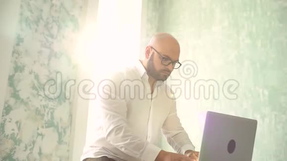 售货员带着笔记本电脑在办公室工作在笔记本电脑上工作的商人或经理有胡子的男人视频的预览图