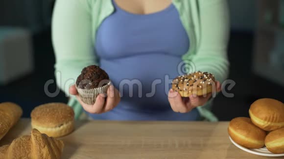女人手里拿着松饼和甜甜圈桌上有很多糕点吃得很多视频的预览图