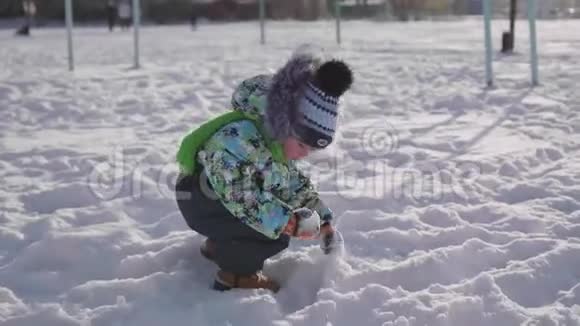 一个小孩在冬天的公园里玩雪阳光明媚的冬天白天新鲜空气中的乐趣和游戏视频的预览图