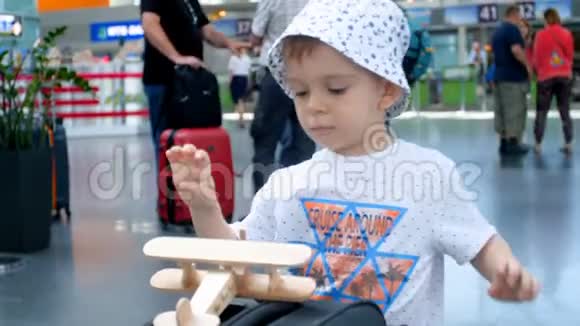 小男孩在从机场候机楼乘飞机前玩木玩具飞机的4k镜头视频的预览图