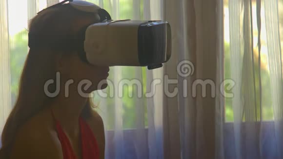 在房间特写镜头中女孩用窗户戴上虚拟现实头盔视频的预览图