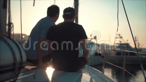 两个朋友在日落时带着游艇看海湾视频的预览图