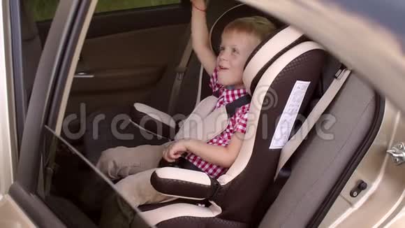 可爱开朗的孩子在夏天的旅程中在孩子们的汽车座位上玩得很开心视频的预览图