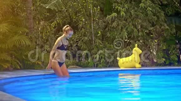 女孩微笑走进绿色植物附近的池水游泳视频的预览图