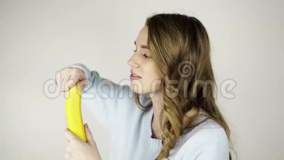 美丽的年轻女子剥着美味的香蕉吃视频的预览图