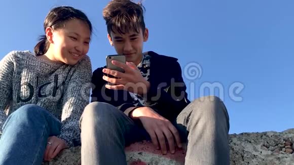 两个青少年坐在街上在电话里看有趣的视频视频的预览图