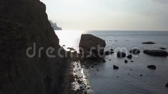 日出时飞越海洋岩石和石头克里米亚卡拉达格山的鸟瞰图视频的预览图